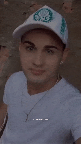 a young man wearing a white hat with a green logo on it