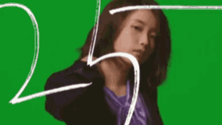 a woman in a suit and a purple shirt is standing in front of a green screen .