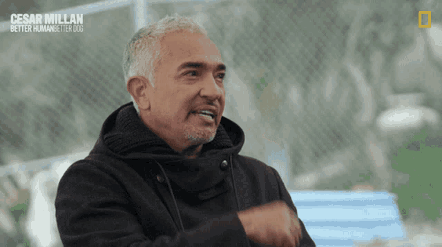 a man in a black coat with the name cesar millan on the bottom right