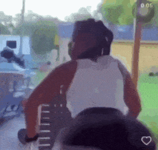 a woman in a white tank top is riding a bike with a heart in the corner