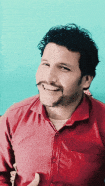 a man in a red shirt with a mustache is smiling for the camera
