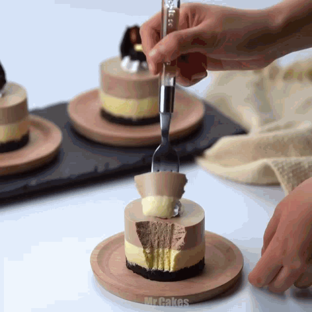 a person is cutting a piece of cake with a fork and the word mrcakes is on the bottom right