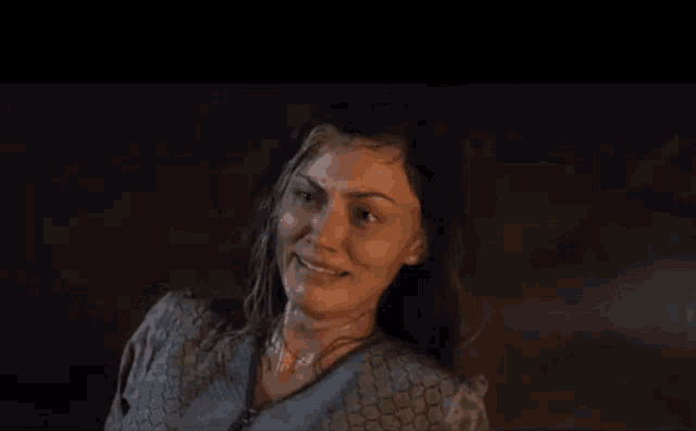 a woman is standing in the dark with her eyes closed and her face wet .