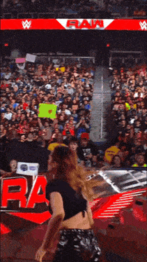 a woman is dancing in front of a crowd at a wrestling event .