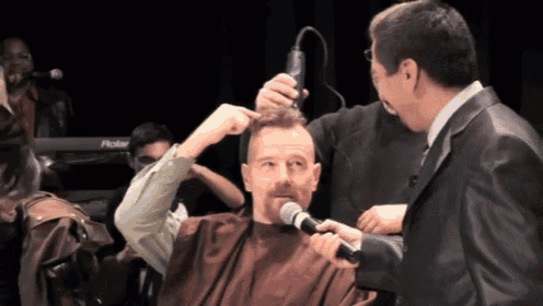 a man is getting his hair cut by a man with a microphone in front of a roland keyboard