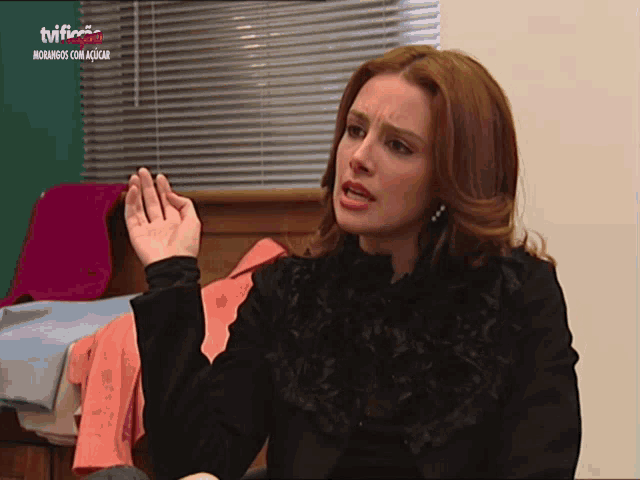 a woman is sitting in front of a tv screen that says ' tvi ' on it