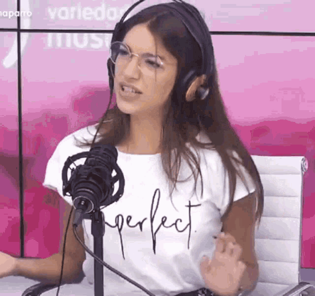 a woman wearing headphones and a perfect t-shirt is talking into a microphone