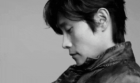 a black and white photo of a man wearing a leather jacket and looking down .