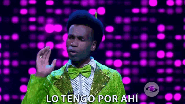 a man wearing a green suit and bow tie says lo tengo por ahi