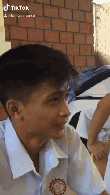 a boy in a school uniform has a tiktok icon on his face