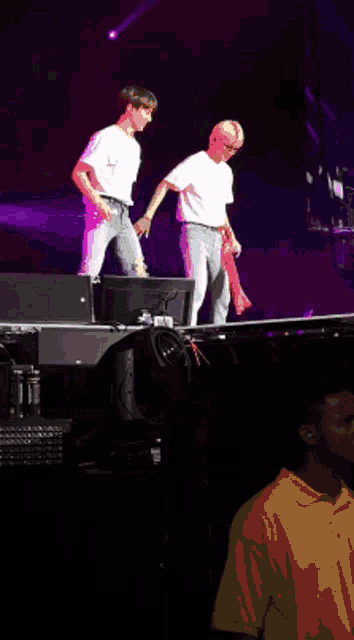 a man in a white shirt is dancing on a stage with another man