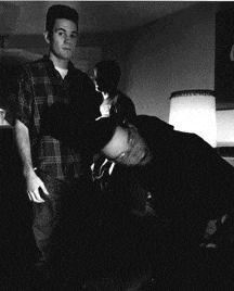 a man in a plaid shirt is standing next to a man laying on the floor
