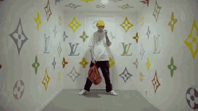 a man standing in front of a wall with louis vuitton symbols painted on it