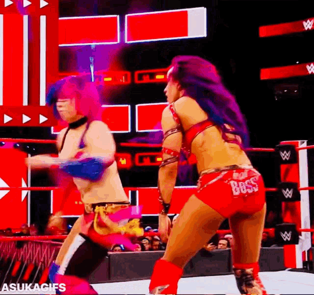 two women are wrestling in a wrestling ring and one of them is wearing red shorts that say rock n ' roll .