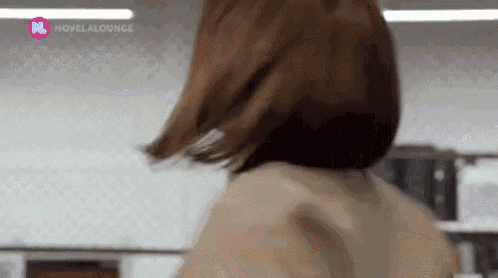 a woman with short brown hair is standing in a room .