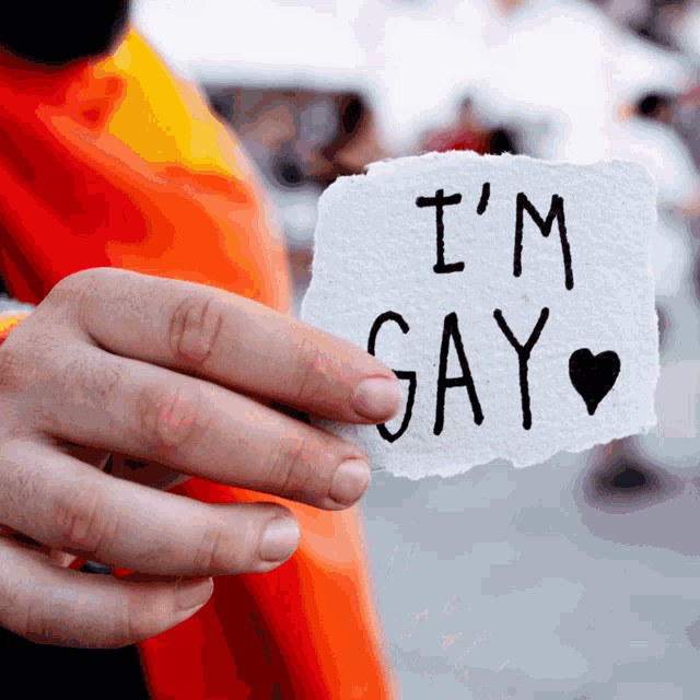 a person holds a piece of paper that says i 'm gay