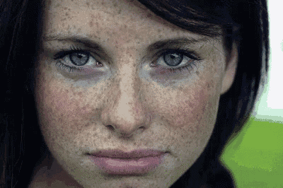 a woman with freckles and blue eyes looks at the camera