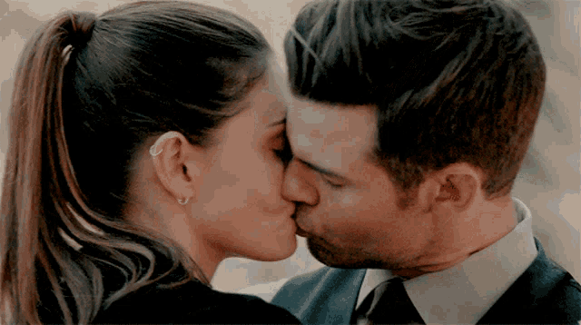 a man and a woman are kissing and the woman is wearing a ponytail