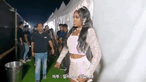 a woman in a white crop top and shorts is walking in front of a crowd of people .