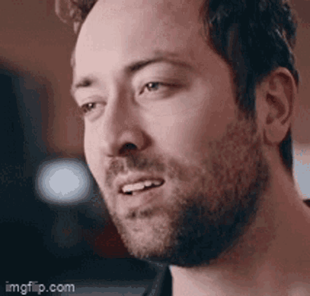 a man with a beard is smiling and looking at the camera