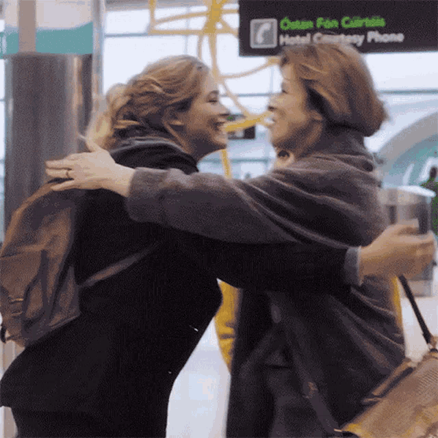 two women hugging in front of a sign that says hotel company