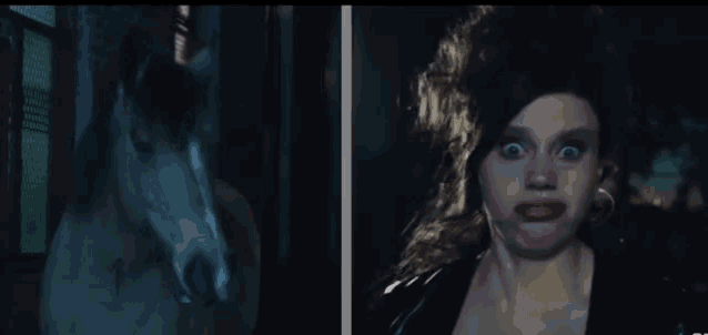 a woman making a funny face next to a horse in a dark room