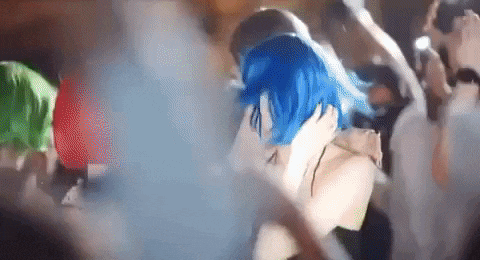 a woman with blue hair is kissing a man at a party .
