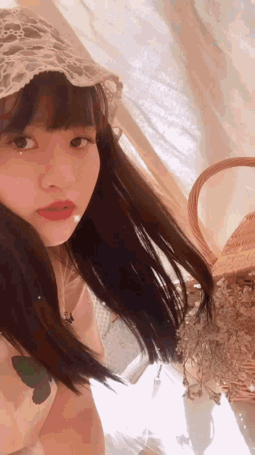 the girl is wearing a lace headband and holding a basket of dried flowers .