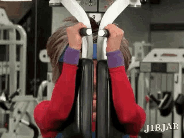 a man is sitting on a machine in a gym covering his face .