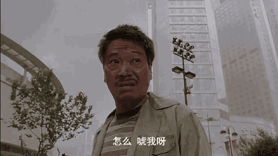 a man with a mustache is standing in front of a tall building and talking to someone .