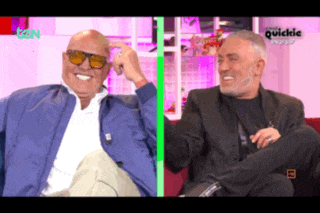two men are sitting next to each other and one is wearing sunglasses and the other is wearing a suit