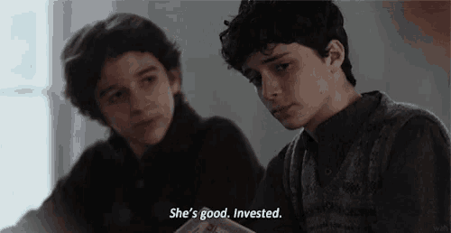 two young boys are sitting next to each other and one of them is saying she 's good . invested .