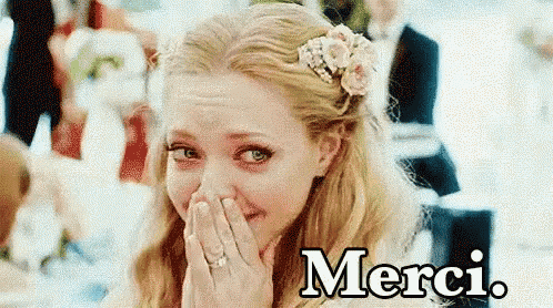 a woman with a flower in her hair is covering her face with her hands and the word merci is above her