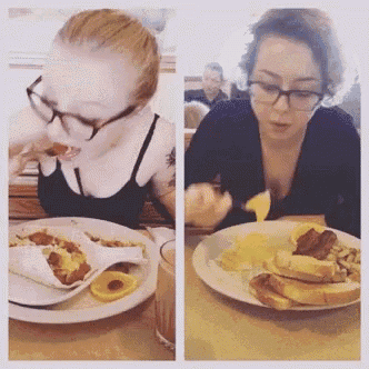 two women are sitting at a table with plates of food and drinks