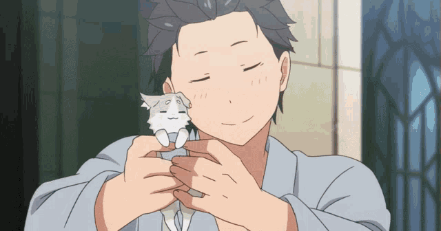 a man with his eyes closed is holding a small white cat in his hands