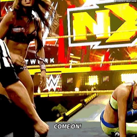 a woman in a bikini is standing in a wrestling ring and saying come on
