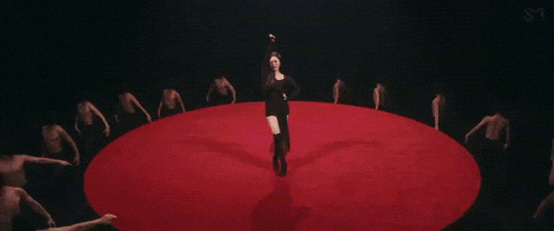 a woman in a black dress is standing in a circle of men