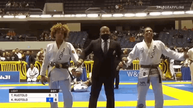 a referee stands between two fighters wearing a rvca kimono