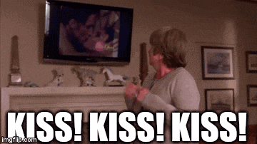 a woman is standing in front of a television and says kiss kiss kiss