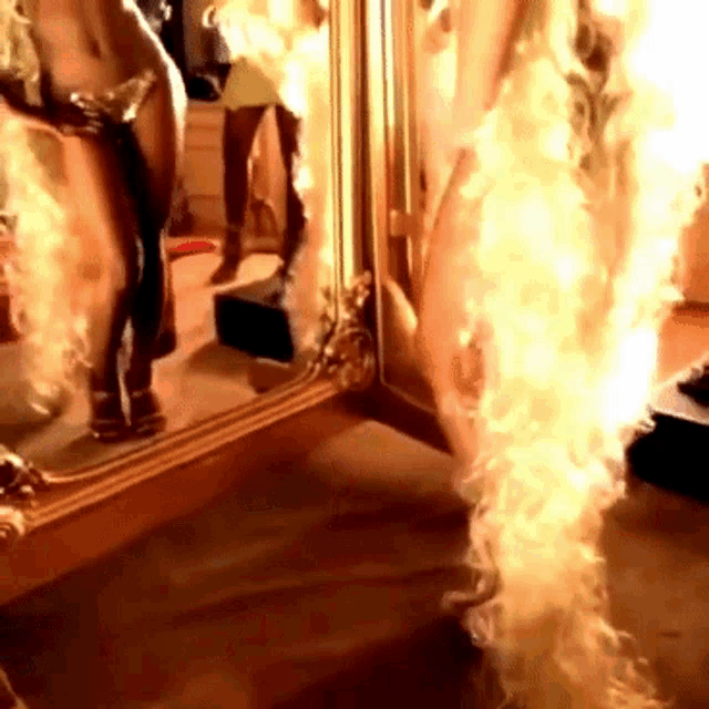 a woman in a bikini is standing in front of a mirror with flames coming out of it