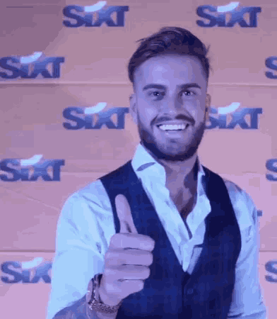 a man with a beard is giving a thumbs up in front of a sixt sign