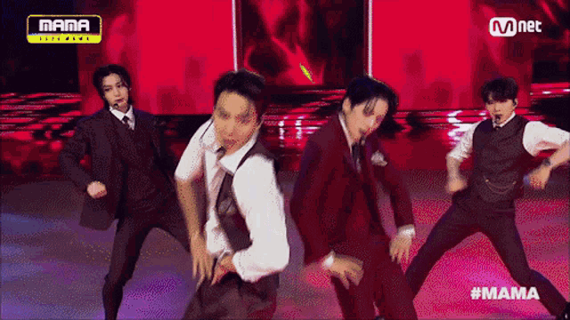 a group of men in suits and ties are dancing on a stage in front of a mnet sign