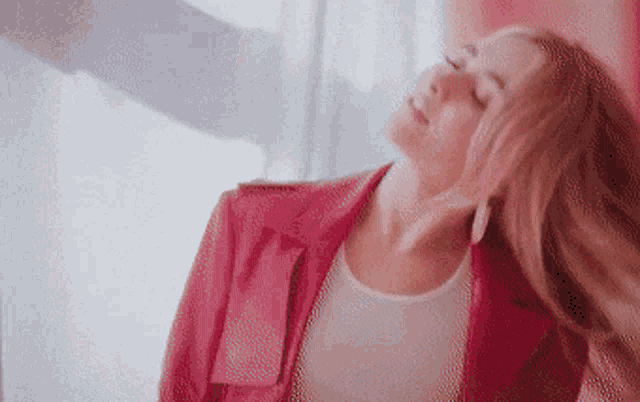 a woman in a red jacket is dancing with her hair in the air .
