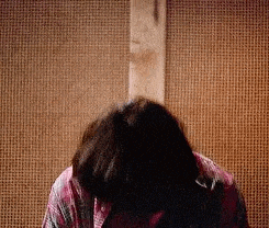 a woman is sitting in front of a wooden wall with her head down .