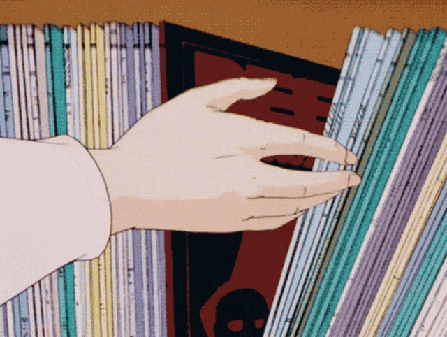 a person 's hand is reaching for a book in a bookshelf