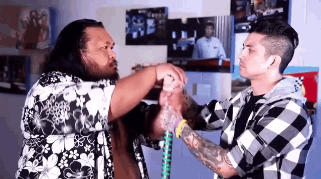a man in a plaid shirt is shaking hands with a man in a floral shirt
