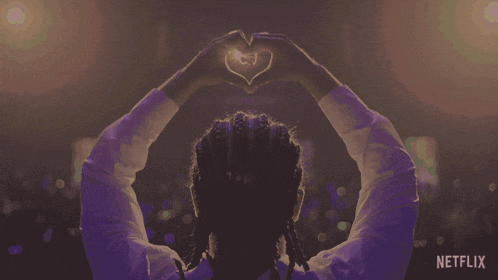 a person making a heart shape with their hands in front of a netflix sign
