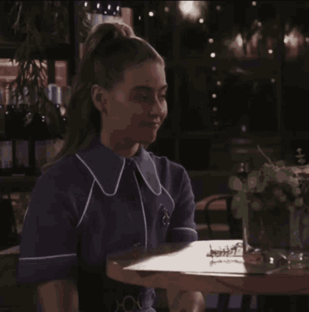 a woman in a purple shirt is sitting at a table with a menu in front of her