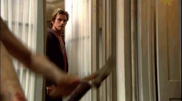 a man in a red shirt with the letter g on it stands in a doorway