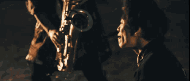 a woman singing into a microphone with a saxophone in the background